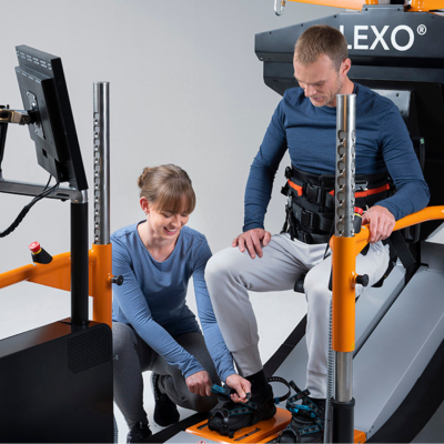 Therapist closes foot attachement of patient on Lexo robotic gait trainer