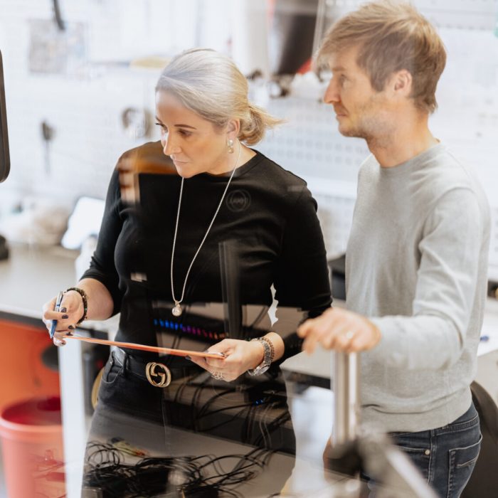 A man and a woman reviewing a Tyromotion therapy device on the production floor.