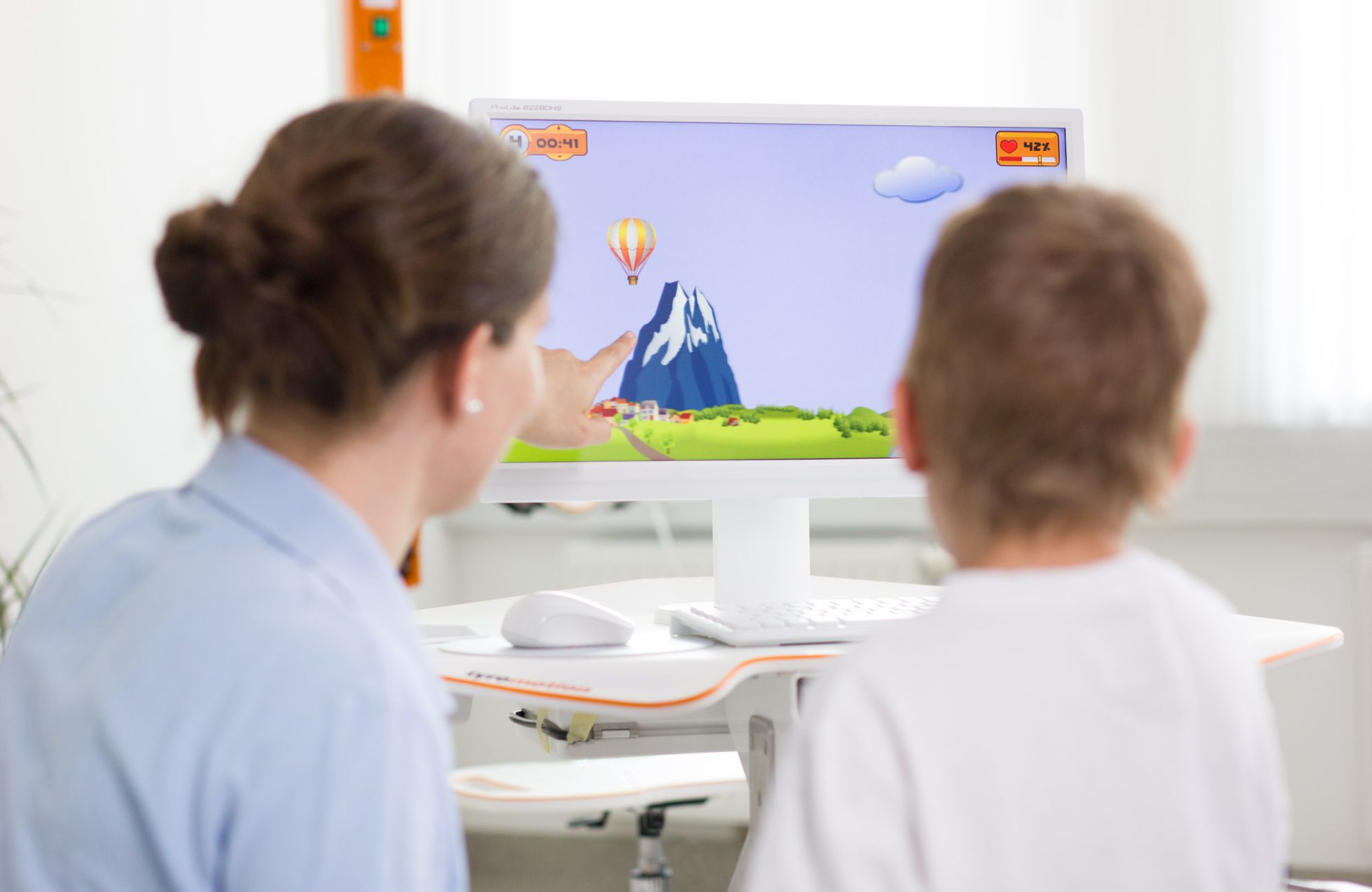 Boy and therapist play game on hand rehabilitation device Amadeo