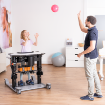 Child throwing ball to therapist on rehabilitation standing frame Elvis