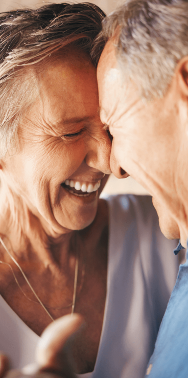 An older woman and an older man laughing together.