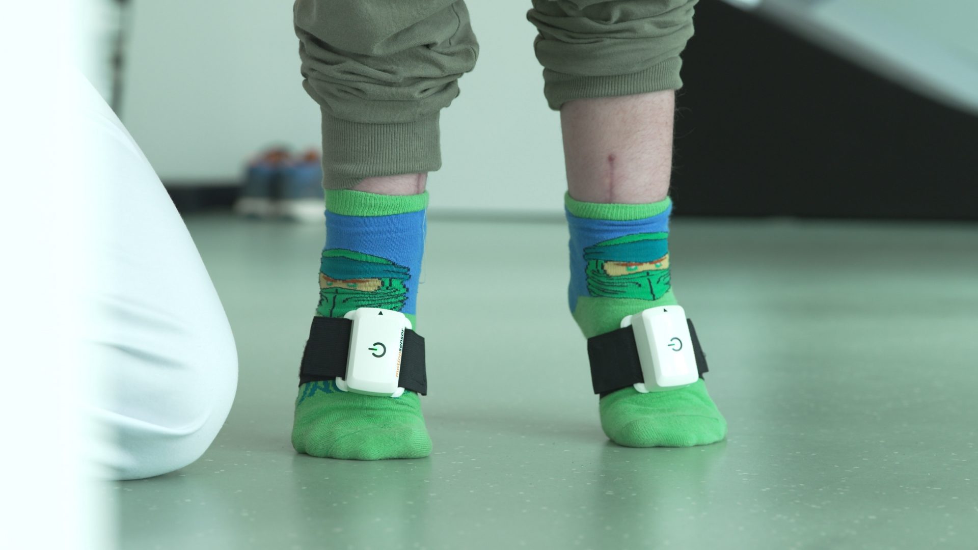 Child with Ninja socks in physiotherapy with Pablo motion sensors on the feet
