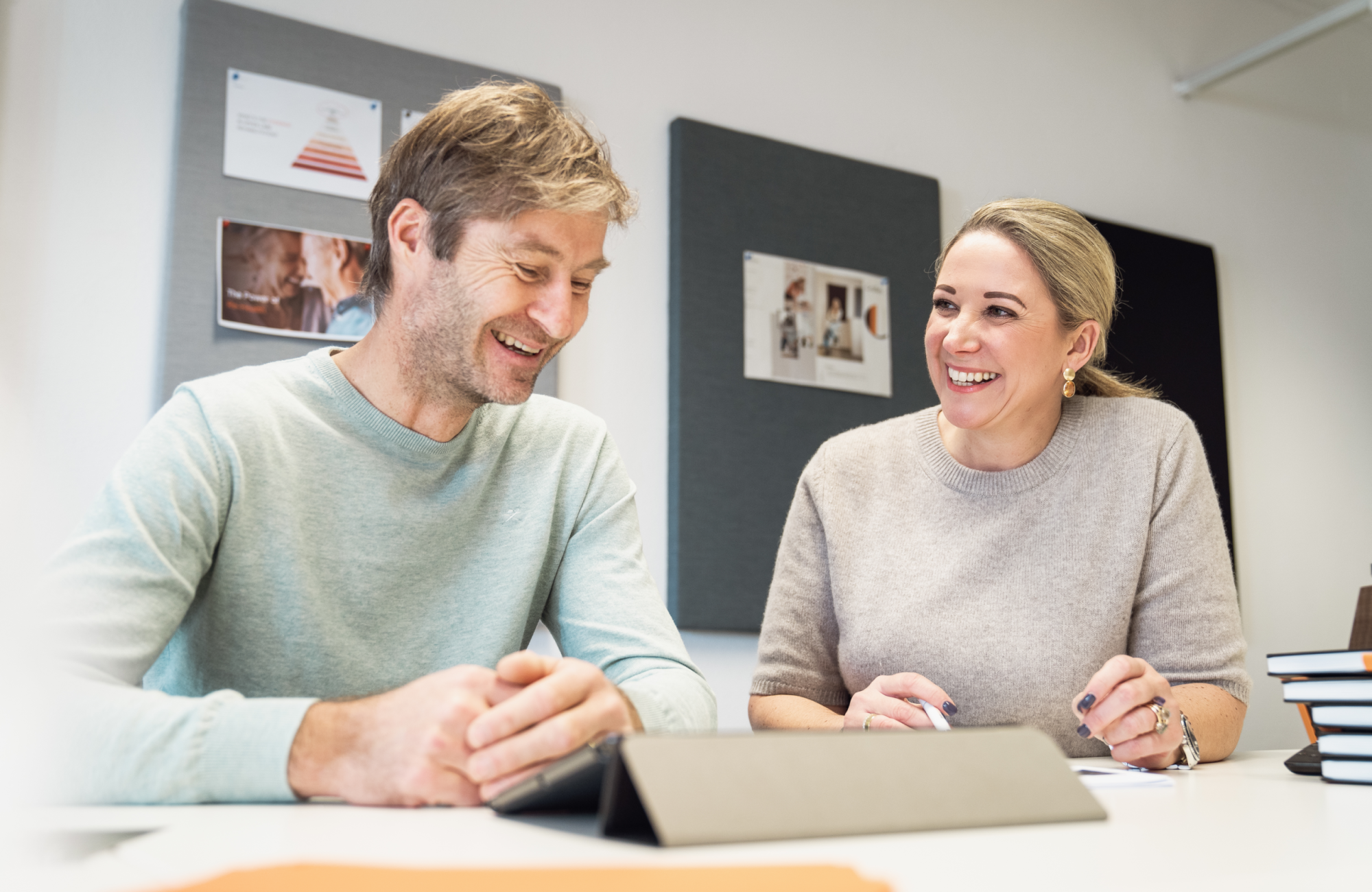 Management Picture from Alexander Kollreider and Verena Schiller, sitting at a desk and talking to each other and smiling.