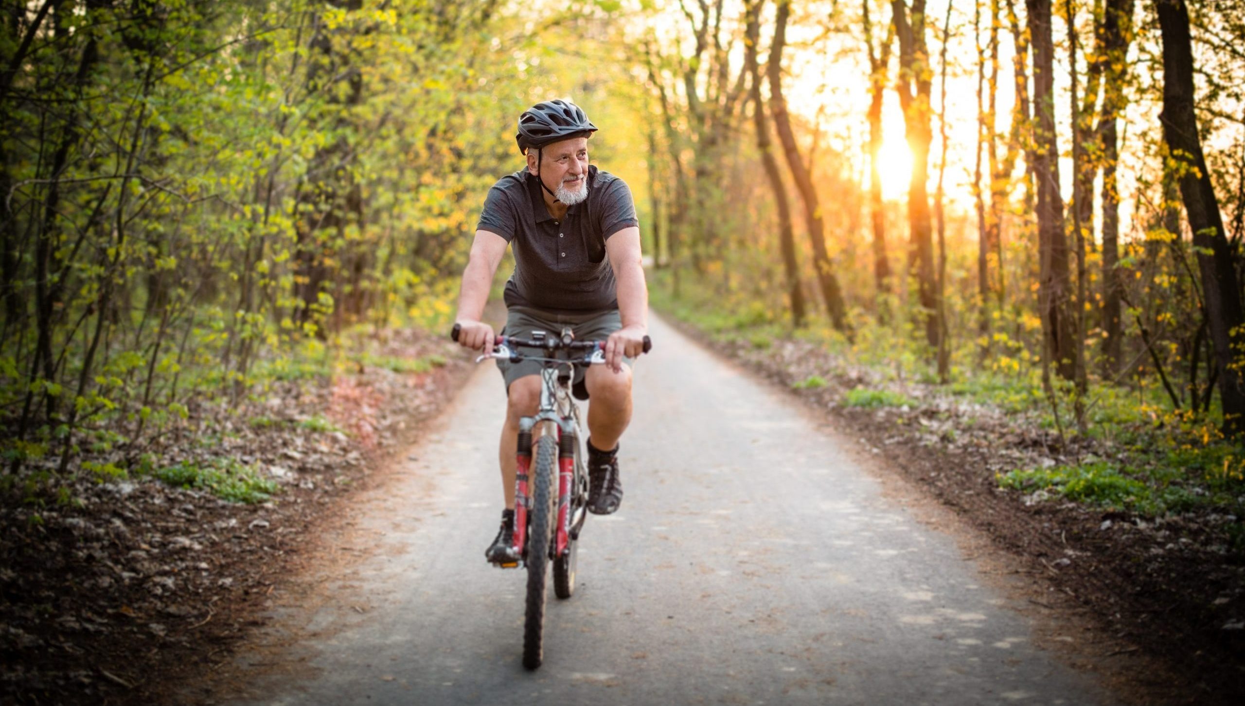 Old men on his mountin bike cycling through a wood