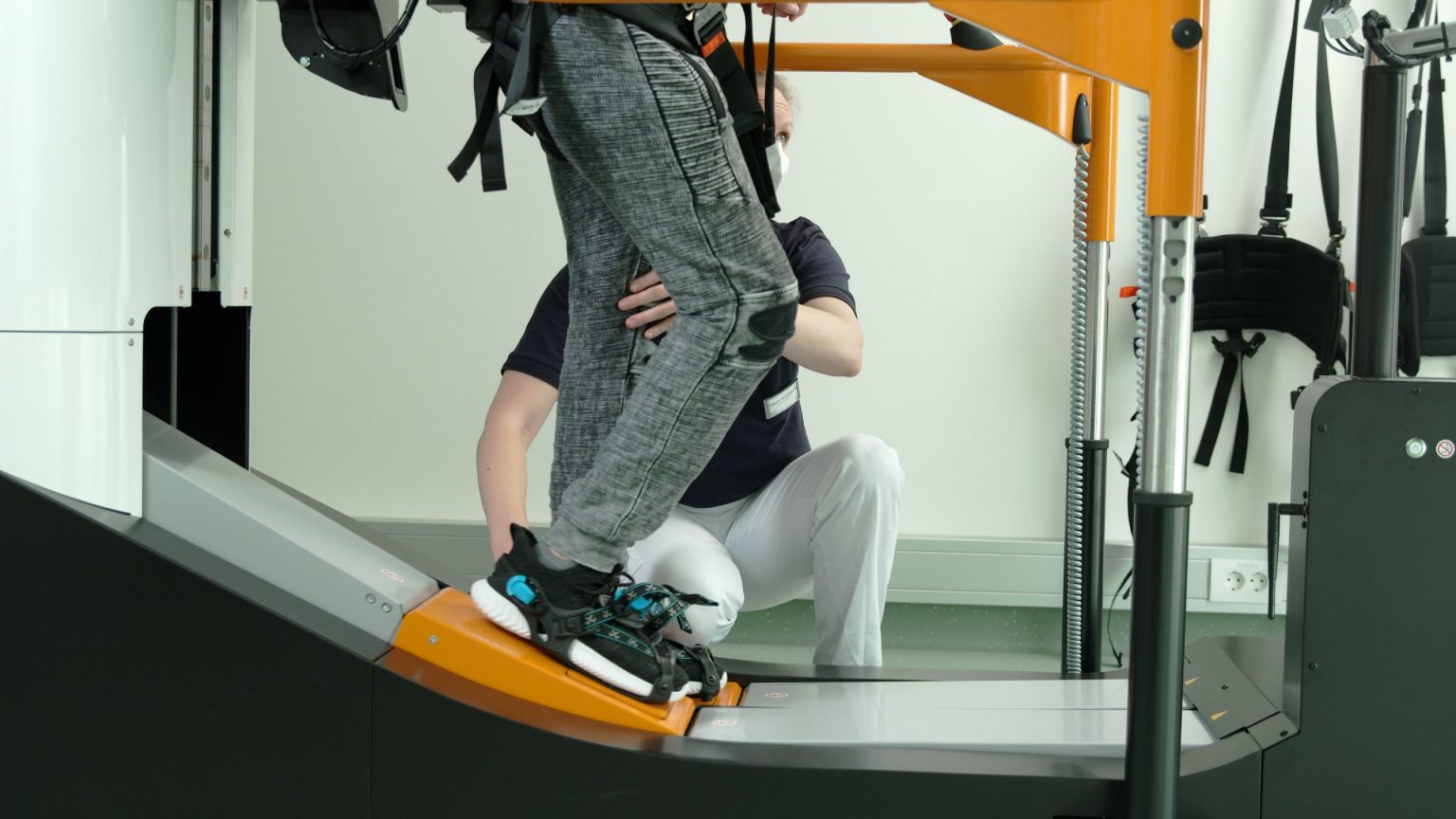 A person in the Lexo gait trainer and one therapist beside supporting