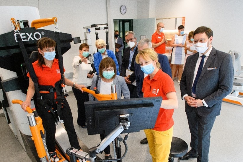 Therapists of GLG Fachklinik Wolletzsee standing beside the gait trainer Lexo. One therapist is in the gait trainer