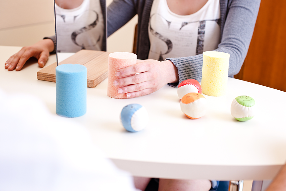 Picture from mirror therapy. A person is grasping things at a table.