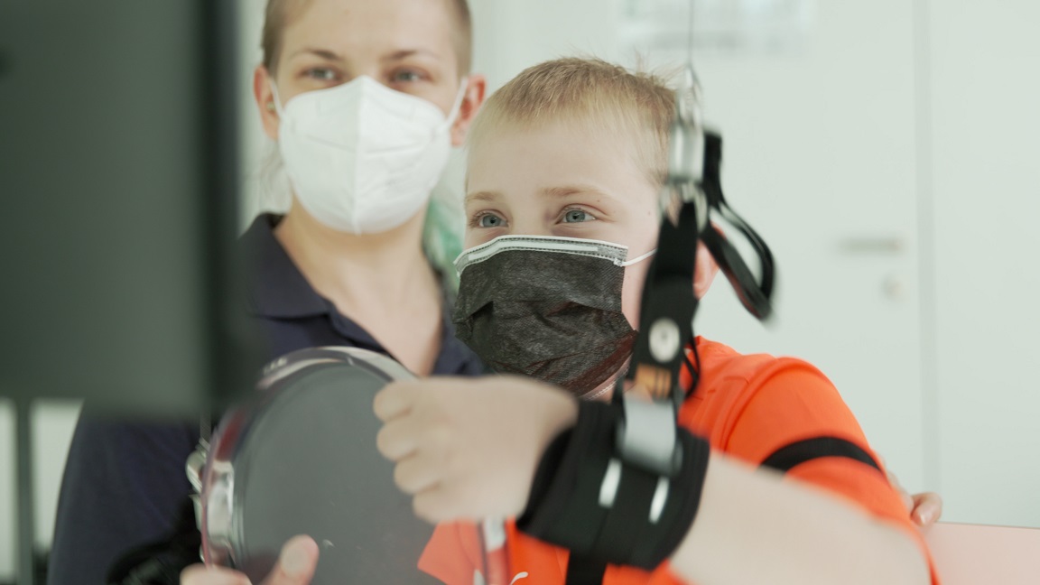 Female Therapist and male young patient in a therapy session. The patient is playing a rehabilitation game with tyroS, using the arm and shoulder rehabilitation device Diego