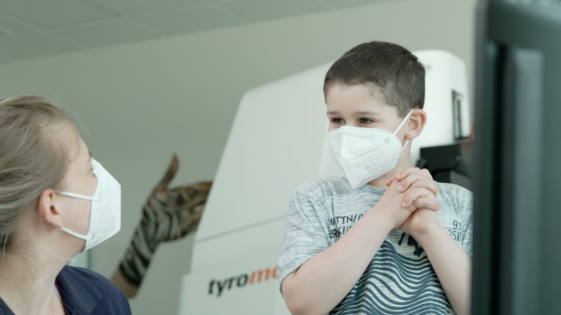 A female therapist and a young male patient in a therpy room. The child has a happy face and wearing a face mask