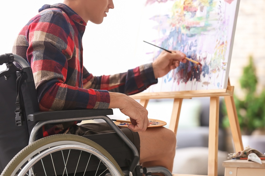 Young artist sitting in a wheelchair and painting a picture