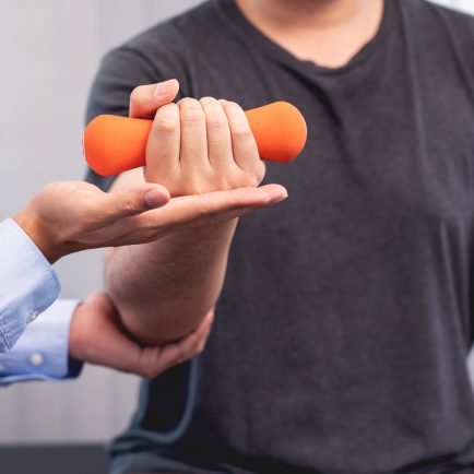 A doctor helping a patient to lift a dumbbell