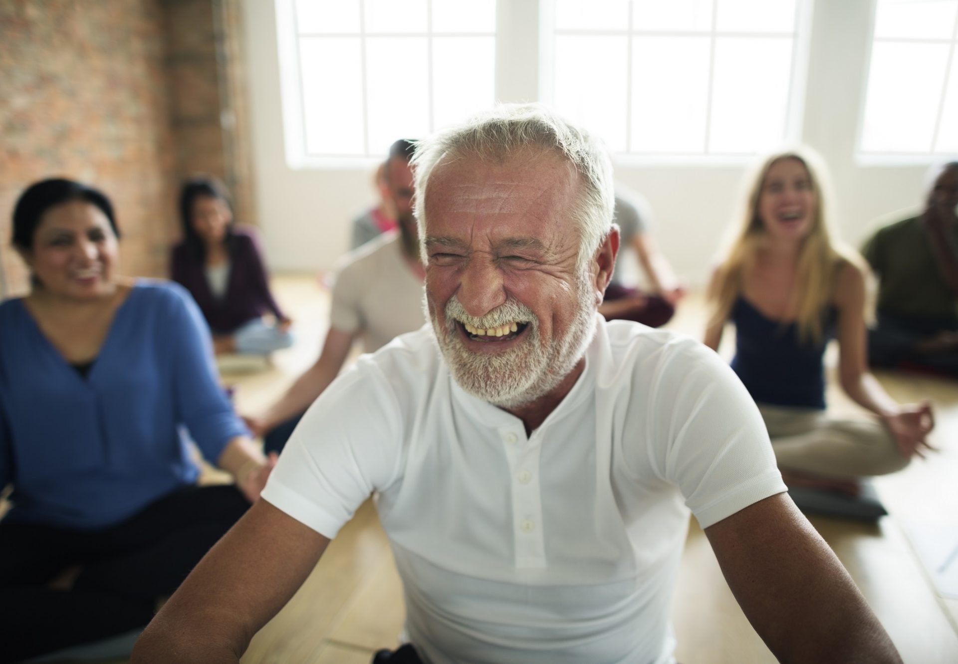 Older man laughing in a Yoga class