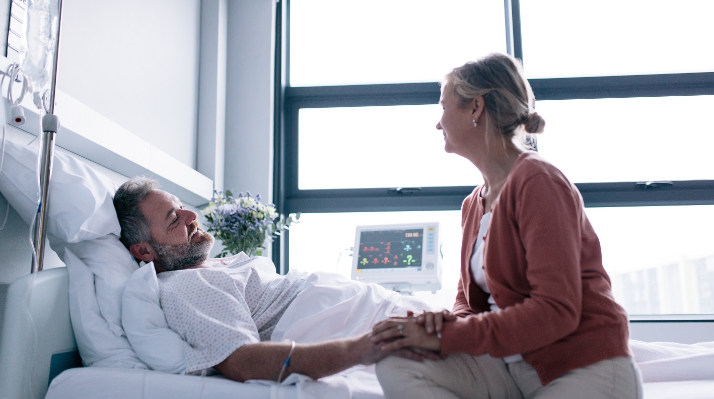 Woman holds the hand of a hospital patient